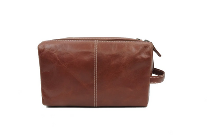 Front view of a brown leather toiletry bag on a white background