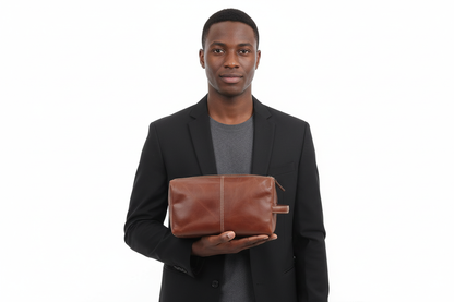 Man holding a brown leather toiletry bag against a white background