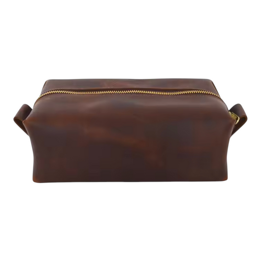 Front view of a brown leather dopp kit with gold zipper on a white background
